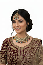 Woman wearing traditional jewelry and attire against a draped curtain background