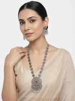 Young woman wearing the Aurelia royal medallion oxidised necklace and oversized Chandbalis, featuring ruby and emerald accents for an elite bridal look.