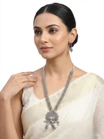 Young woman wearing the Kira artisanal long-line necklace with a flute-player pendant, styled as elite evening jewellery to showcase the lightweight antique finish and intricate sunburst design.