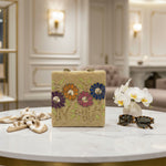 A beige floral handcrafted tote bag with glass beads embroidered on it, displayed on a wooden surface.