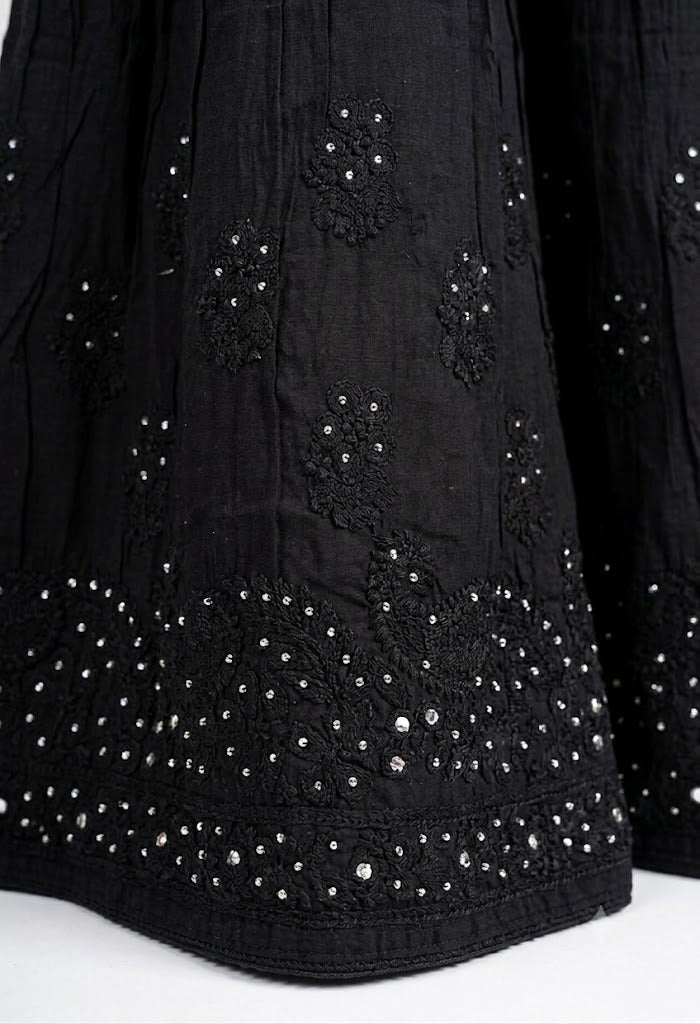 Close-up of a black cotton gharara featuring intricate antique silver kaamdani work and delicate black thread bakhiya embroidery on the flared hem.
