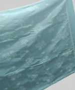 A blue cotton saree with floral embroidery and a blouse piece, draped over on a dummy