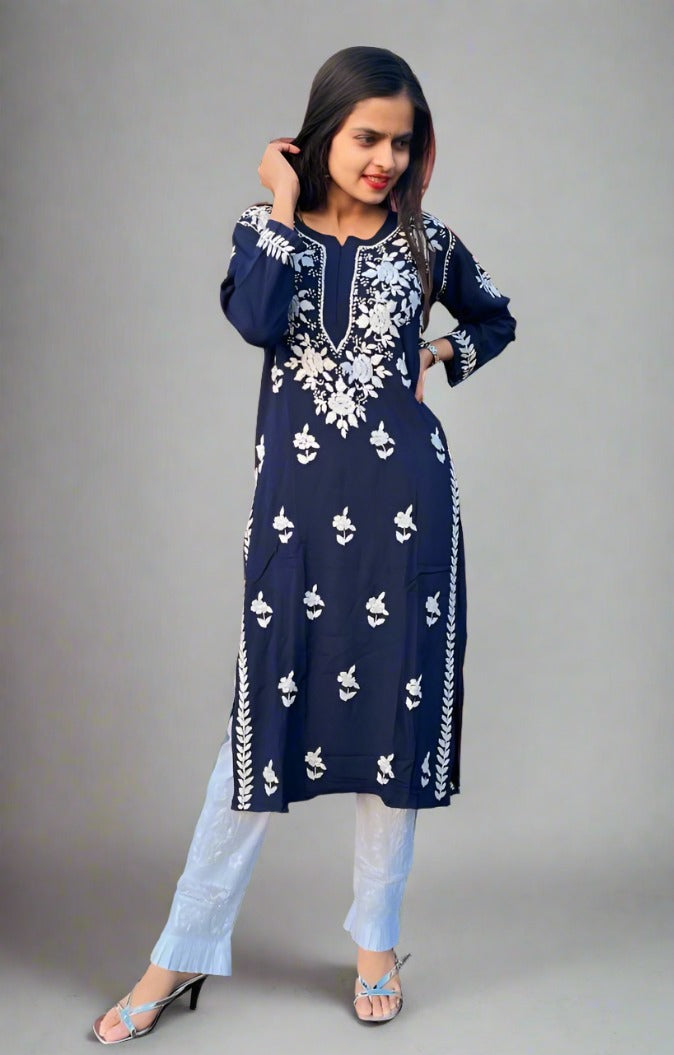 A woman wearing a navy blue Chikankari kurti with Ghass Patti embroidery, paired with white trousers and heels.