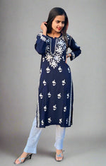 A woman wearing a navy blue Chikankari kurti with Ghass Patti embroidery, paired with white trousers and heels.