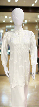 A white Chikankari short kurti displayed on a mannequin, featuring intricate hand embroidery with floral motifs.