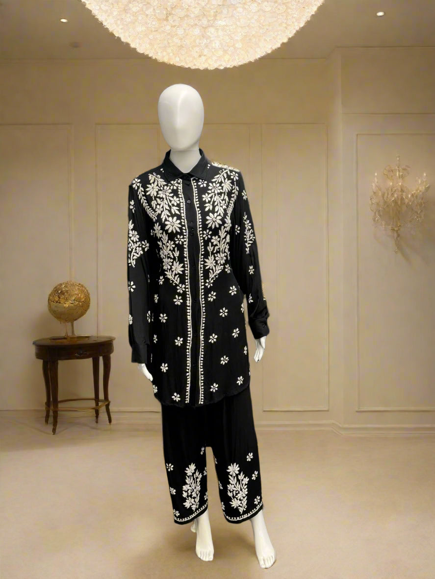 A traditional black with white floral embroidered cord set displayed on a mannequin, consisting of a front-open shirt and matching trousers.