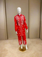 A traditional red and white floral embroidered cord set displayed on a mannequin, consisting of a front-open shirt and matching trousers.