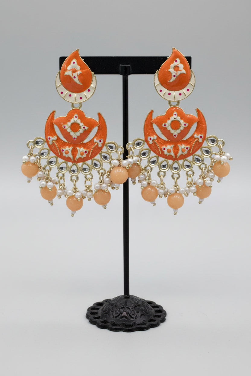 enamel painted orange colour Pair of earrings displayed on a stand.