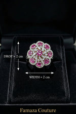 The Famaza Couture Royal Magenta-Pink Floral Cluster Statement Ring displayed inside a luxury black velvet presentation box, highlighting its detailed silver-tone crystal setting and vivid magenta stones.