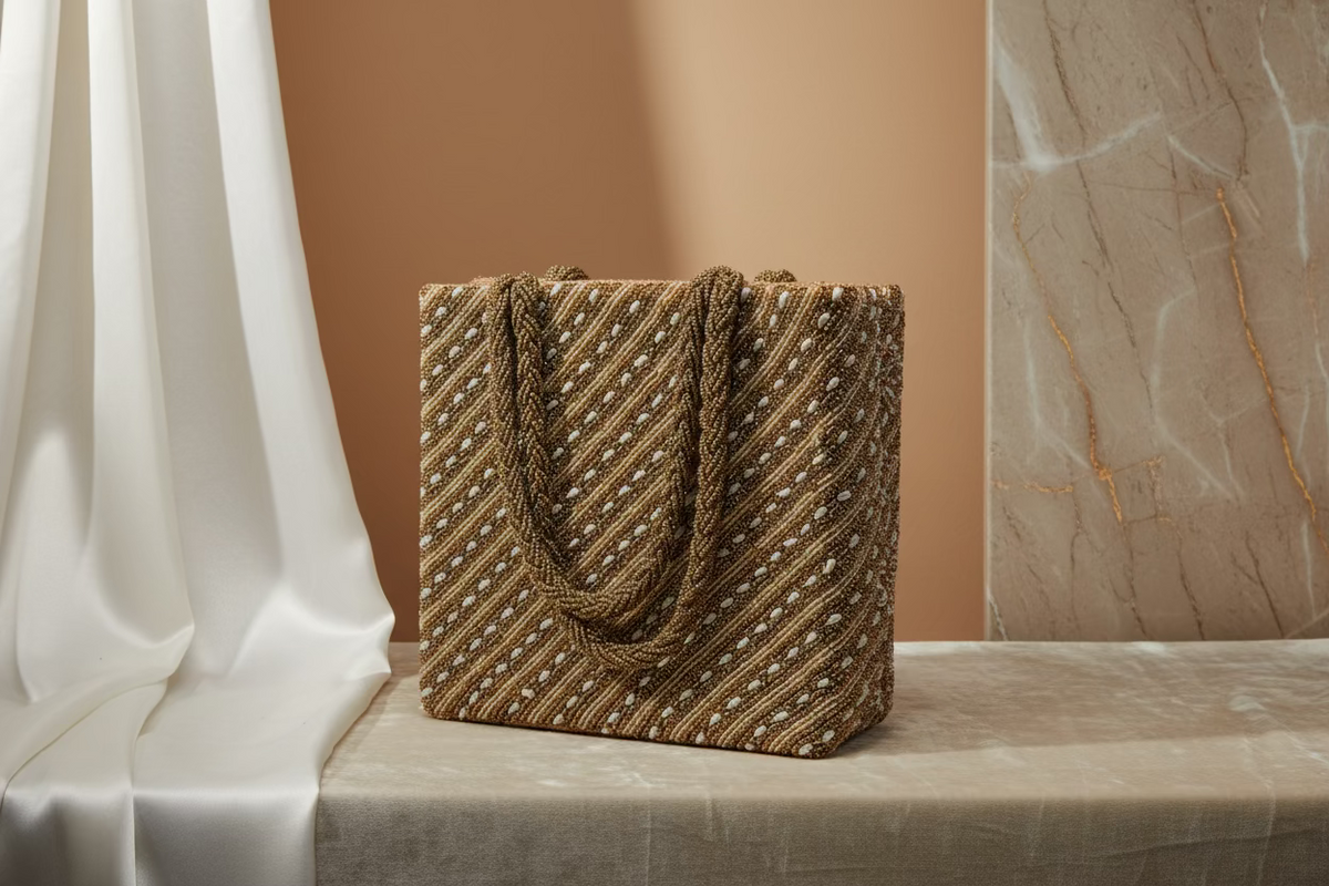 A tote bag with gold diagonal lines and long beads handcrafted on a gold silk base.