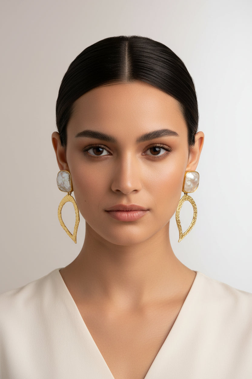 A pair of golden 3D leaf detailed earrings on a display stand, showcasing the earrings' full design and craftsmanship.