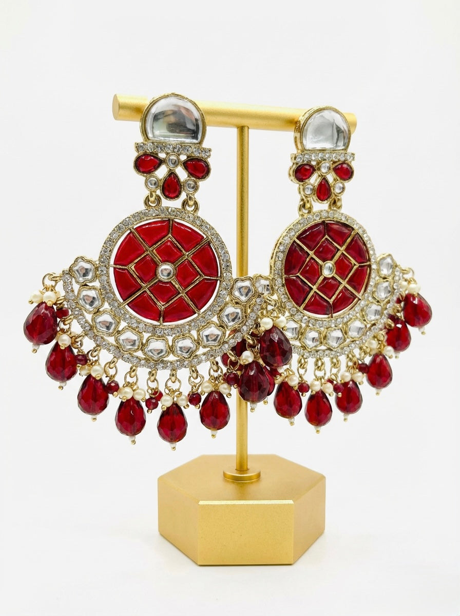 Front view of large maroon Chandbali earrings with crystal halos and hanging red droplets worn by our model.