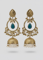 Ornate gold earrings with black stones and pearl-like beads on a textured surface.
