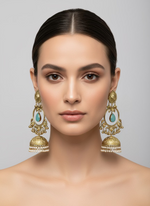 Ornate gold earrings with turquoise stones on a white card, held by a hand.