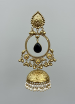 Hand holding a gold earring with black stone in front of a display of similar earrings.