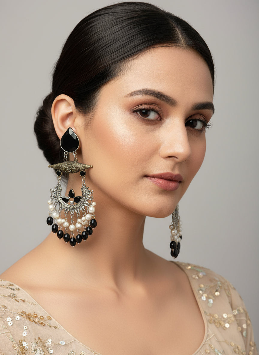 Decorative earrings with black and white details on a textured white surface