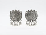 Close-up of matching oxidised silver-tone lotus earrings with engraved petals and dangling ghungroo beads
