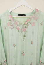 Close-up of pink floral and green leaf embroidery around the neckline of a mint green kurta