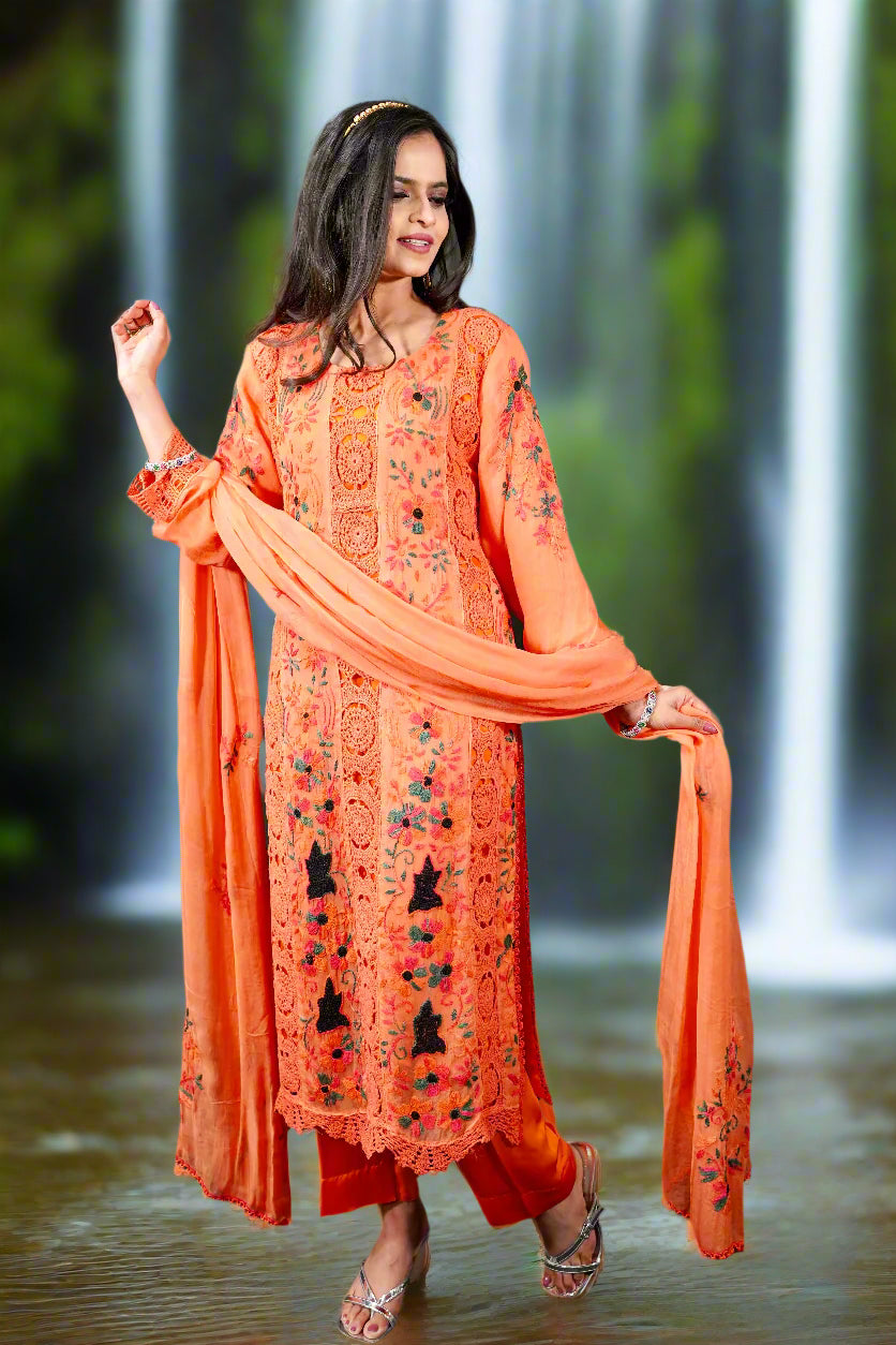 Model wearing orange floral embroidered Pakistani chiffon suit with dupatta and pants