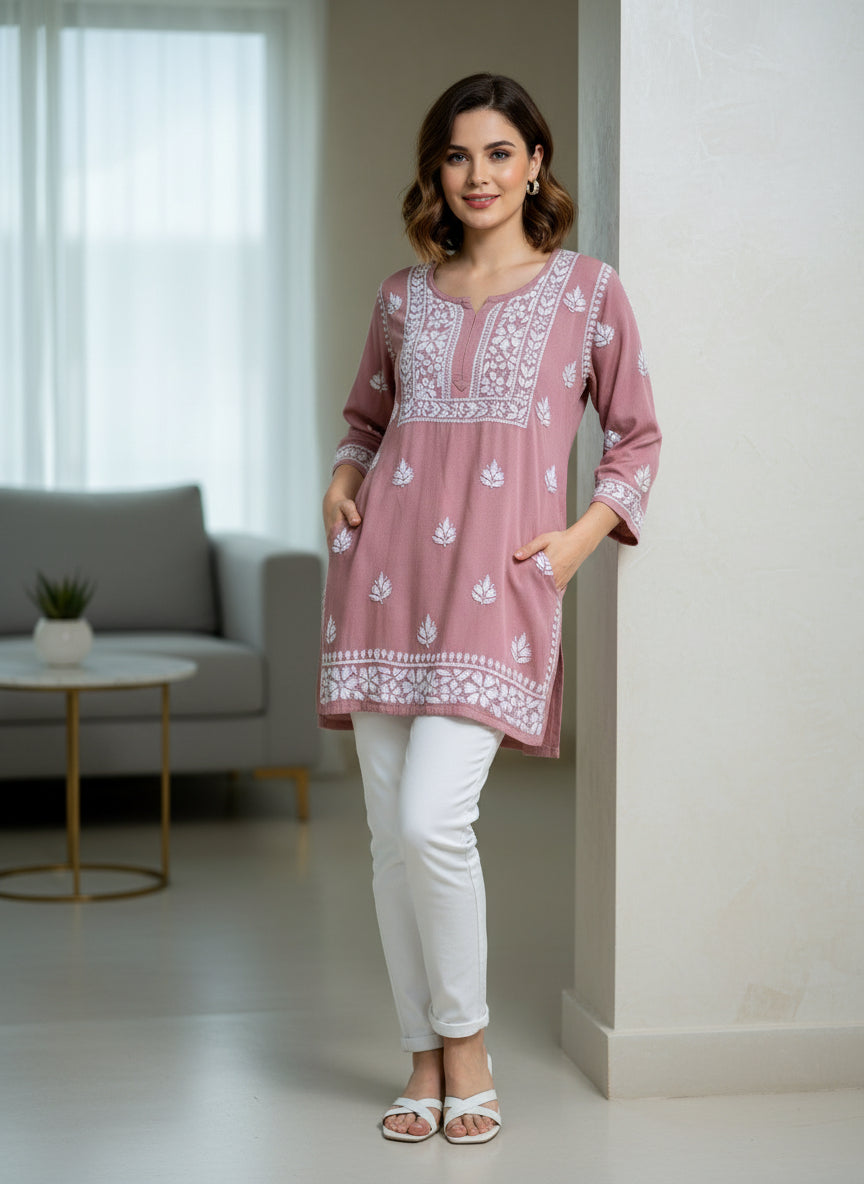 model is wearing and posing in this tea pink colour short length Chikankari kurti with white floral hand embroidery with white jeans