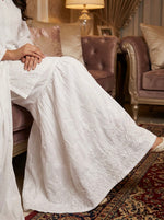 model is wearing and showing the flare of the white cotton gharara trousers.