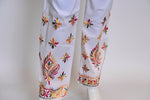 A pair of white stretchable cotton pants with pockets both sides and multicolour thread floral embroidery, featuring a relaxed fit with an adjustable drawstring waistband.
