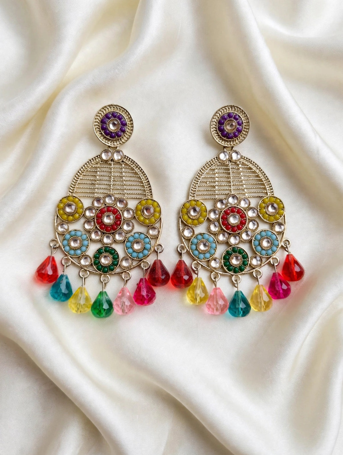 Pair of antique gold-tone teardrop earrings with purple stud tops, multicolour floral detailing and colourful drops on cream satin.