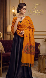 Woman wearing a mustard yellow shawl with intricate patterns over a black dress in an elegant room.