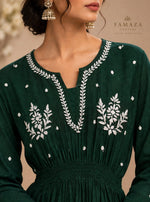 A bottle green long-sleeve dress with white floral embroidery around the V-neckline and on the chest.