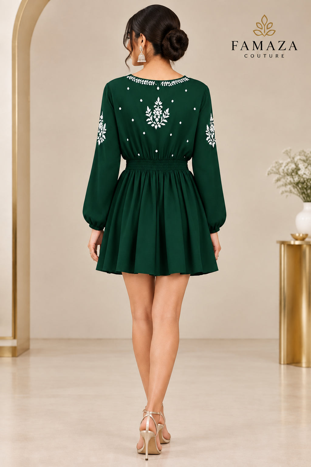A rear view of a bottle green long-sleeve dress with white embroidered details on the bodice, sleeves, and neckline.