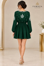 A rear view of a bottle green long-sleeve dress with white embroidered details on the bodice, sleeves, and neckline.