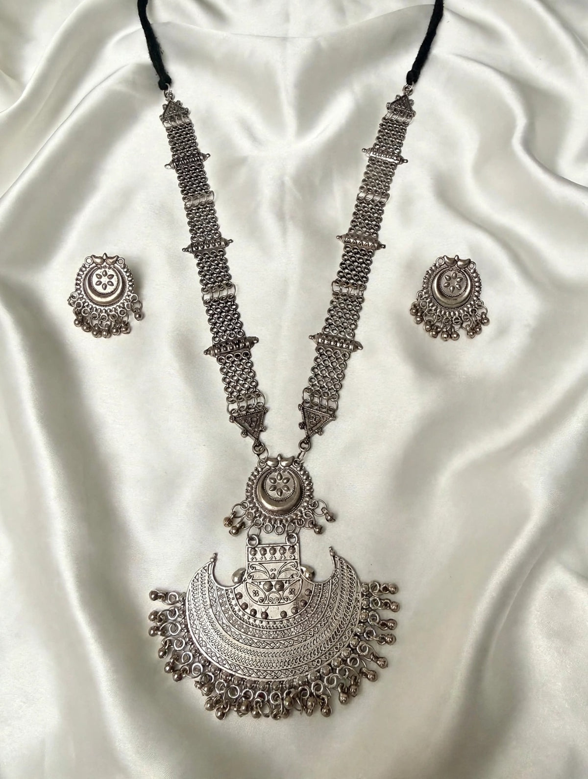 Oxidised silver Afghan Rani Haar Y-shaped necklace set — large crescent pendant, stud mini jhumka earrings, black dori cord — pendant 8.5cm drop x 8cm wide, chain 13cm drop, 25g — on cream silk.