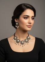 Decorative belt with pearls and intricate metalwork on a white stand.