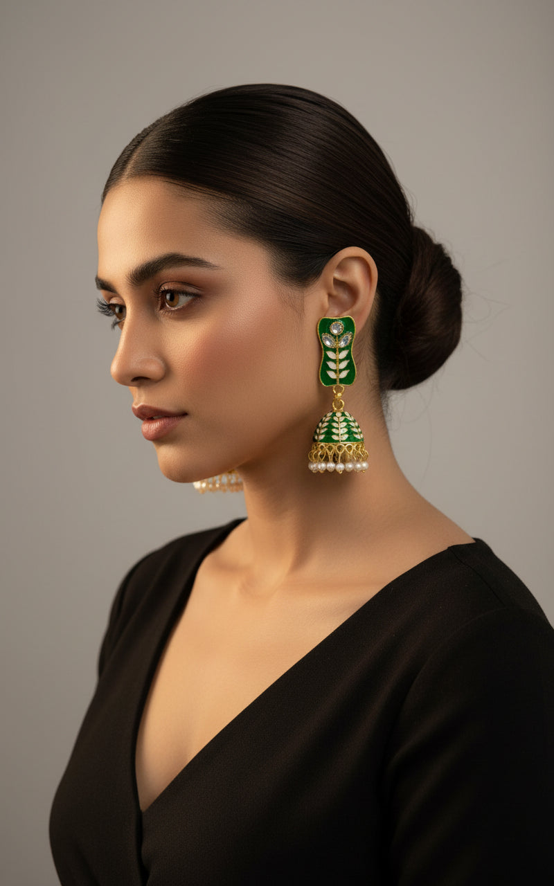 pair of gold-plated Bottle Green colourMeenakari drop Jhumka earrings displayed on a stand, featuring intricate designs and studded with stones.