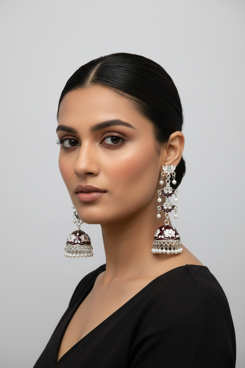 pair of maroon colour silver-plated tulip-shaped long jhumka earrings with multicolour details, displayed on a black stand.