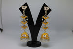pair of mustard colour silver-plated tulip-shaped long jhumka earrings with multicolour details, displayed on a black stand.
