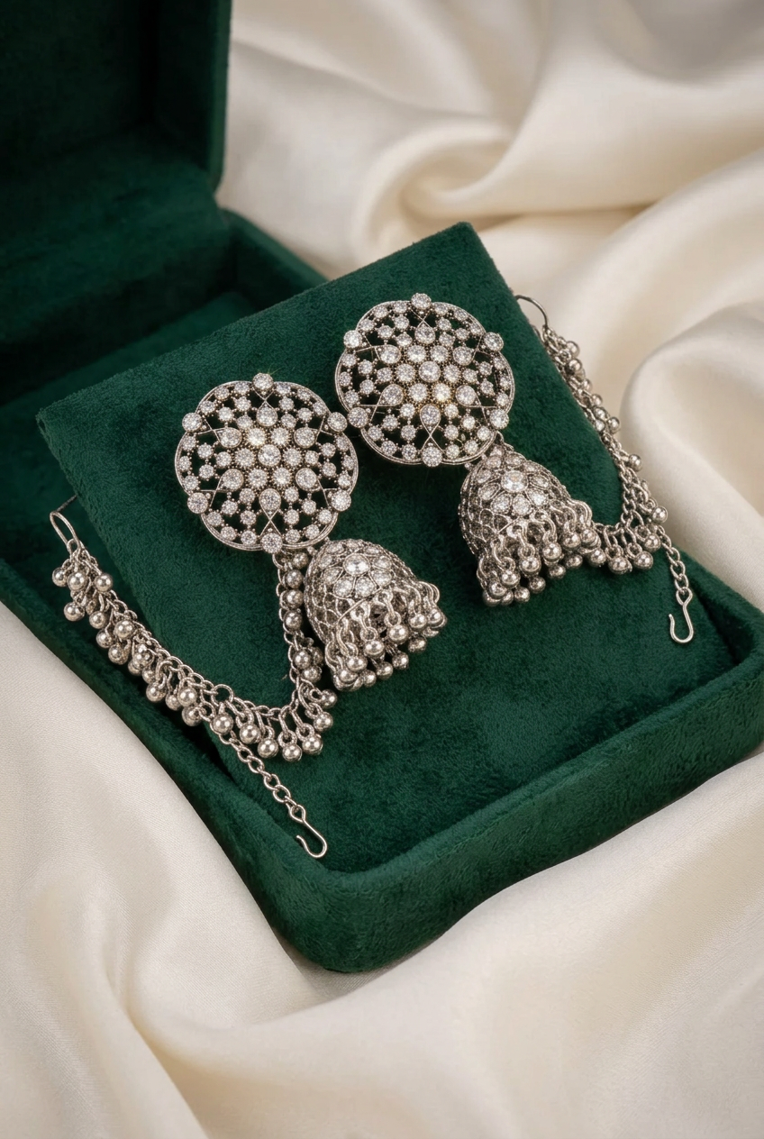 Pakeezah Moonlight jhumka earrings with clear stones and beaded Sahara chains on a green velvet display.
