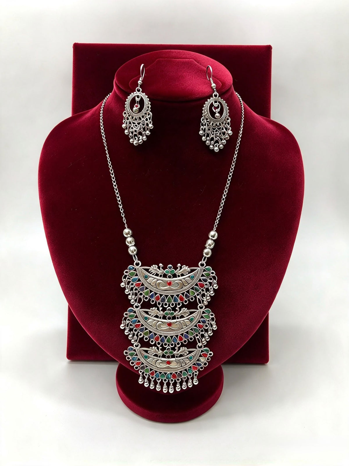 Peacock Radiance oxidised triple pendant necklace with multicolour accents and matching hook earrings on a red velvet stand