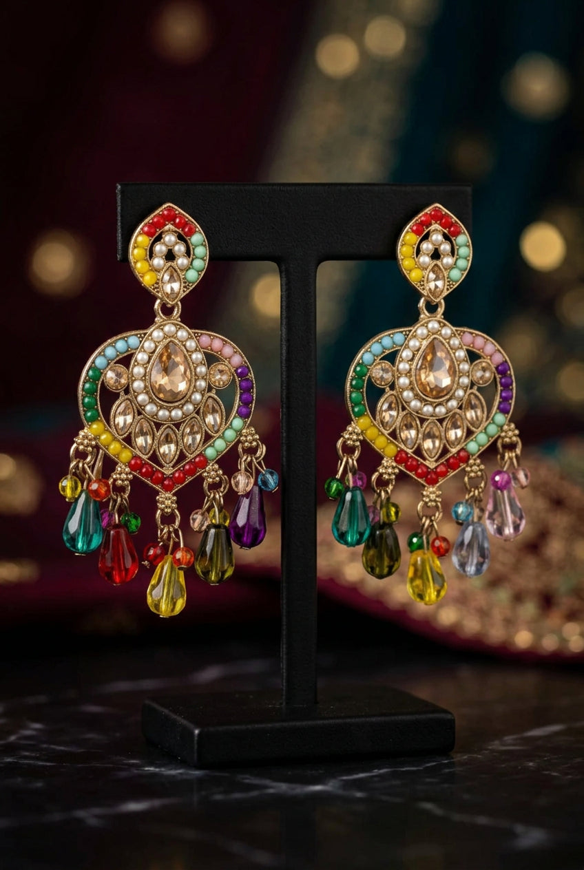 Heart-shaped chandelier earrings on a black stand, with multicolour detailing, champagne-coloured accents and dangling teardrop beads.