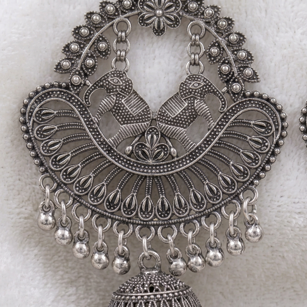 Close-up of paired elephant motifs, ornate openwork and dangling beads on a Silver Serenade chandbali earring.