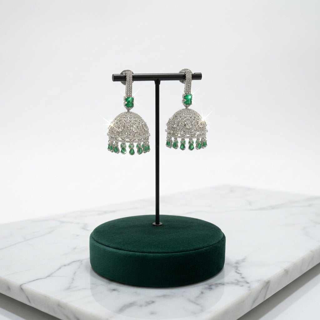 Model wearing a silver-tone green stone jhumka earring, with labelled measurements of 5.5 cm length, 5 cm dome width and 0.5 cm top width.