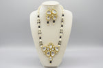 Front view of a black and cream beaded Kundan necklace with a gold-tone pendant and matching drop earrings.