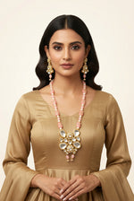 Model wearing a pink beaded Kundan necklace with a gold-tone pendant and matching pink drop earrings.