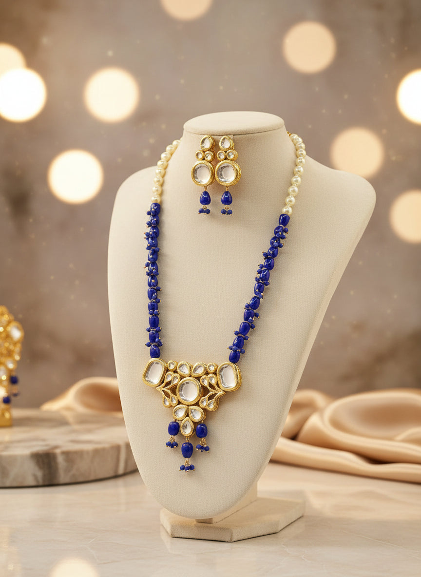Royal blue beaded Kundan Rani Mala necklace and matching drop earrings on a cream display bust.