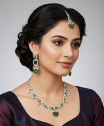 white AD (Artificial Diamond) jewellery set inlcudes a necklace a maang tikka and two earrings with emarlad green centre stones by famaza couture