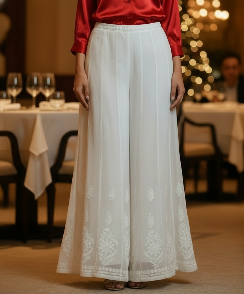 model is wearing white chikankari embroidered flared trousers in a party
