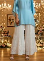 White embroidered dress with yellow top on a wooden floor.