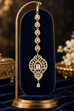 Zara gold-tone maang tikka headpiece with clear stones and a teardrop pendant on a blue velvet stand