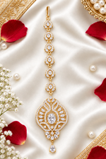 Zara gold-tone American diamond maang tikka laid on ivory satin beside rose petals and pearls