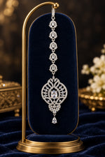 zara silver-tone maang tikka headpiece with clear stones and a teardrop pendant on a blue velvet stand